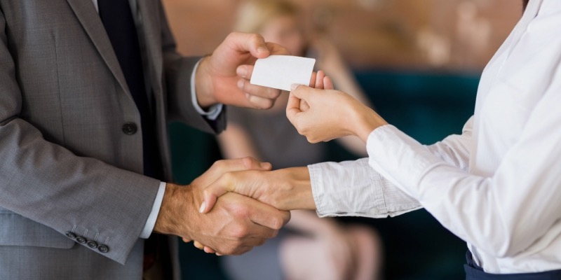 Close up of two people shaking hands and exchanging a business card