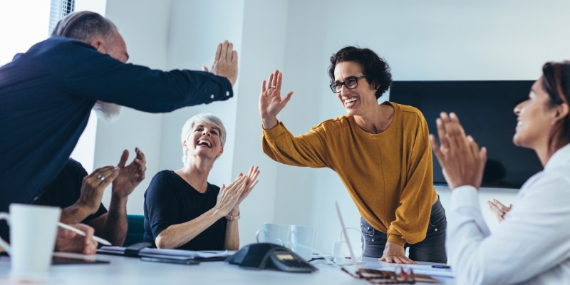People at work with their hand in the air about to 'high five' each other in a motivational praise like manner